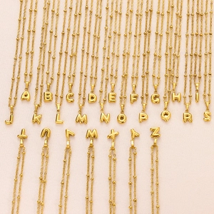 Macro detail of 26 18K gold-plated bubble letter pendants on satellite chains