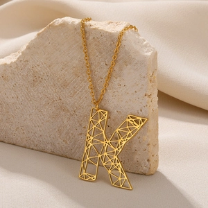Gedetailleerde weergave van een gouden ketting met een holle letter K hanger