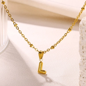 Macro shot of 18K gold plated bubble letter L pendant on a beaded chain necklace