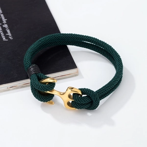 Detailed close-up of dark green braided nautical anchor bracelet with polished gold plating