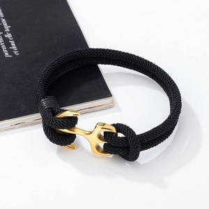 Close-up of gold anchor buckle on black braided rope bracelet with polished finish