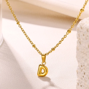 Macro shot of 18K gold plated letter D bubble pendant on beaded cable chain necklace