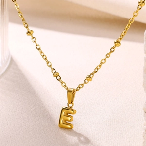 Macro shot of 18K gold plated letter E bubble pendant on a decorative beaded chain