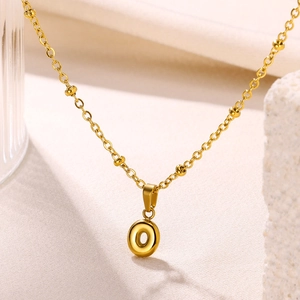 Detailed macro view of 18K gold plated bubble letter O pendant on a beaded chain necklace