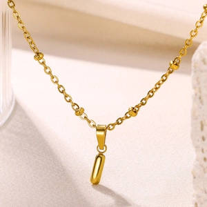 Macro shot of minimalist 18K gold-plated stainless steel capsule pendant on bead chain
