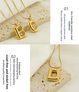 Macro detail of gold bubble 26 initial letter pendant necklaces in polished stainless steel
