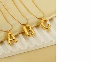 Detailed macro of gold bubble alphabet pendants A B C on sleek snake chain