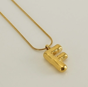 Macro detail of puffy letter F balloon pendant on a gold snake chain necklace