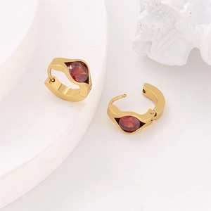 Detail view of gold earrings with oval red gemstone and vacuum plated steel texture