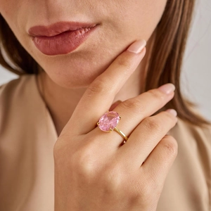 Elegant gold ring with large oval pink gemstone worn by model in a soft lighting