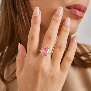 Close-up of elegant oval pink gemstone ring on model finger with golden thin band