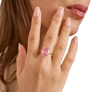 Luxurious gold ring featuring a large oval pink topaz gemstone on a model's hand