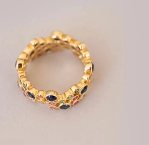 Makroaufnahme von böhmischem dreifachem Wellenring mit bunten Edelsteinen in Gold