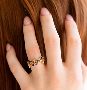 Detail eines böhmischen Goldrings mit bunten Edelsteinen, am Finger getragen