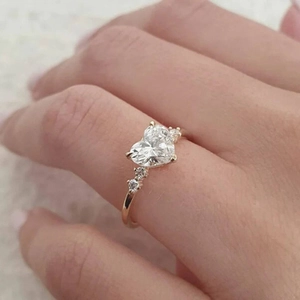 Eleganter goldener Ring mit herzförmigem Moissanit-Stein an einer Frauenhand