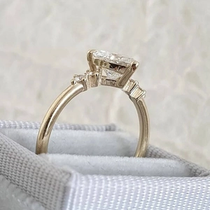 Eleganter goldener Ring mit Smaragdschliff-Strass auf einer grauen Schmuckschatulle
