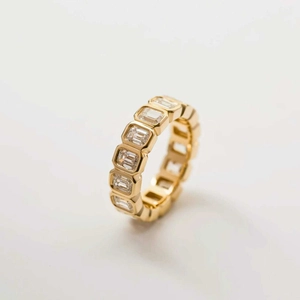 Minimalist gold eternity ring featuring emerald cut square zircons in a bezel setting