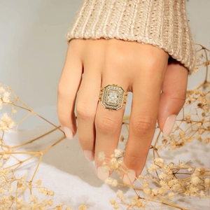 Elegant gold halo ring with emerald cut moissanite and pave band on model hand