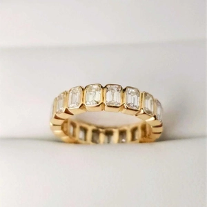 Macro shot of gold eternity ring with emerald-cut rectangular cubic zirconia stones