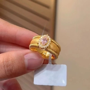 Macro view of vintage style gold woven ring with pink oval stone and diamond halo
