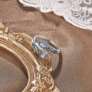 Dettaglio di anello in argento vintage con rilievi e due pietre di luna blu a goccia