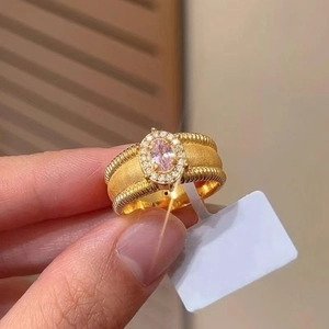 Detailed macro view of brushed gold ring with pink oval gemstone and diamond halo