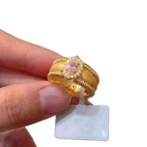 Vintage gold textured ring with oval pink gemstone and diamond halo on white background