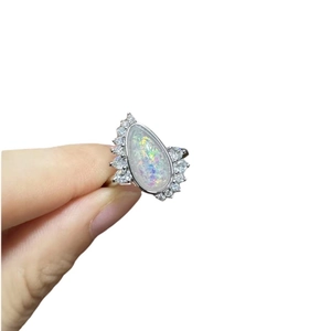 Elegant silver teardrop opal ring with diamond accents and colorful rainbow fire