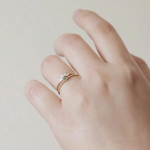 Eleganter Goldring in Kronenform mit grünen Edelsteinen, getragen an einer Hand
