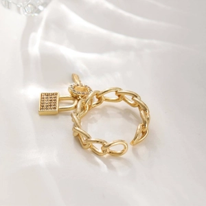 Elegante gouden kettingring met kristallen hangslot en cirkelbedels op witte zijde