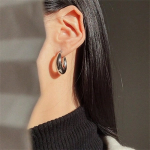 Orecchini a cerchio a U in argento lucido indossati da modella con ombre eleganti