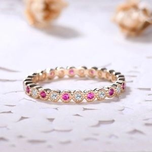 Dettaglio macro di un anello d'oro con pietre rosa e diamanti bianchi su pizzo bianco