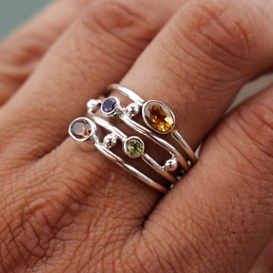 Dettaglio di set di anelli bohémien in argento con gemme colorate sulla mano
