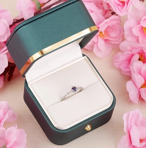 Blue gemstone ring with small diamonds in a premium green velvet gift box and petals