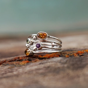 Macro di un anello in argento multistrato con gemme colorate su legno naturale