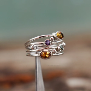 Anello in argento stile bohémien con pietre colorate a strati tenuto da una pinzetta