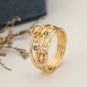 Dettaglio di anello bohémien dorato multistrato con intarsi di pietre preziose colorate