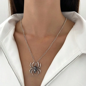 Detail shot of a gothic silver spider pendant necklace worn over a white shirt