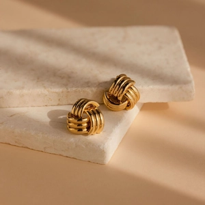 Orecchini a cerchio intrecciati in oro minimalisti su eleganti pietre di travertino
