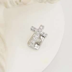Gedetailleerde close-up van een zilveren kruis ear cuff met glanzende zirkonia steentjes