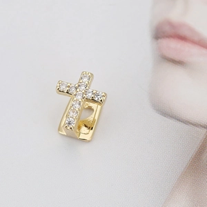 Detail van gouden kruis tandsieraad met zirkonia micro-pave en hartvormig uitgesneden design