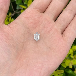 Macro-opname van een kleine kruishanger met micro-ingelegde zirkoon in een palm