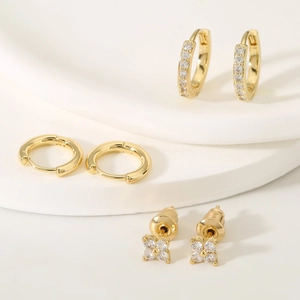 Chic gold-plated clover earrings and pavé zircon hoop set on a white stone pedestal