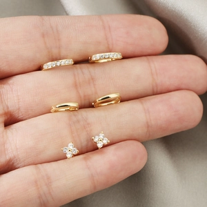 Chic gold-plated clover earrings set with cubic zirconia stones on silk background