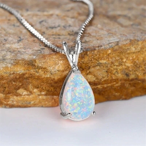 Close-up of a pear-cut opal necklace with vibrant fire on a rustic stone texture