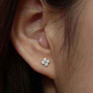 Close-up of four-petal flower stud earring with sparkling crystals and gold finish