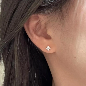 Close-up of elegant silver clover earrings with sparkling crystals worn by a model