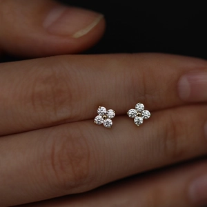 Close-up of gold-plated clover earrings with sparkling white cubic zirconia stones