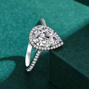 Elegant pear-shaped halo ring with pavé diamonds on a polished silver band