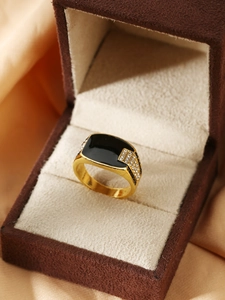 Dettaglio macro dell'anello dorato da uomo con smalto nero e accenti di zircone